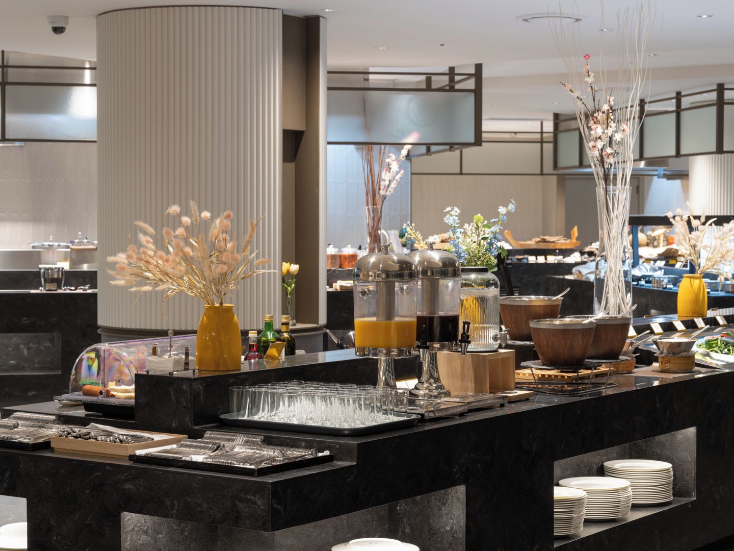 A buffet setup with various food containers, glassware, and decorative elements.