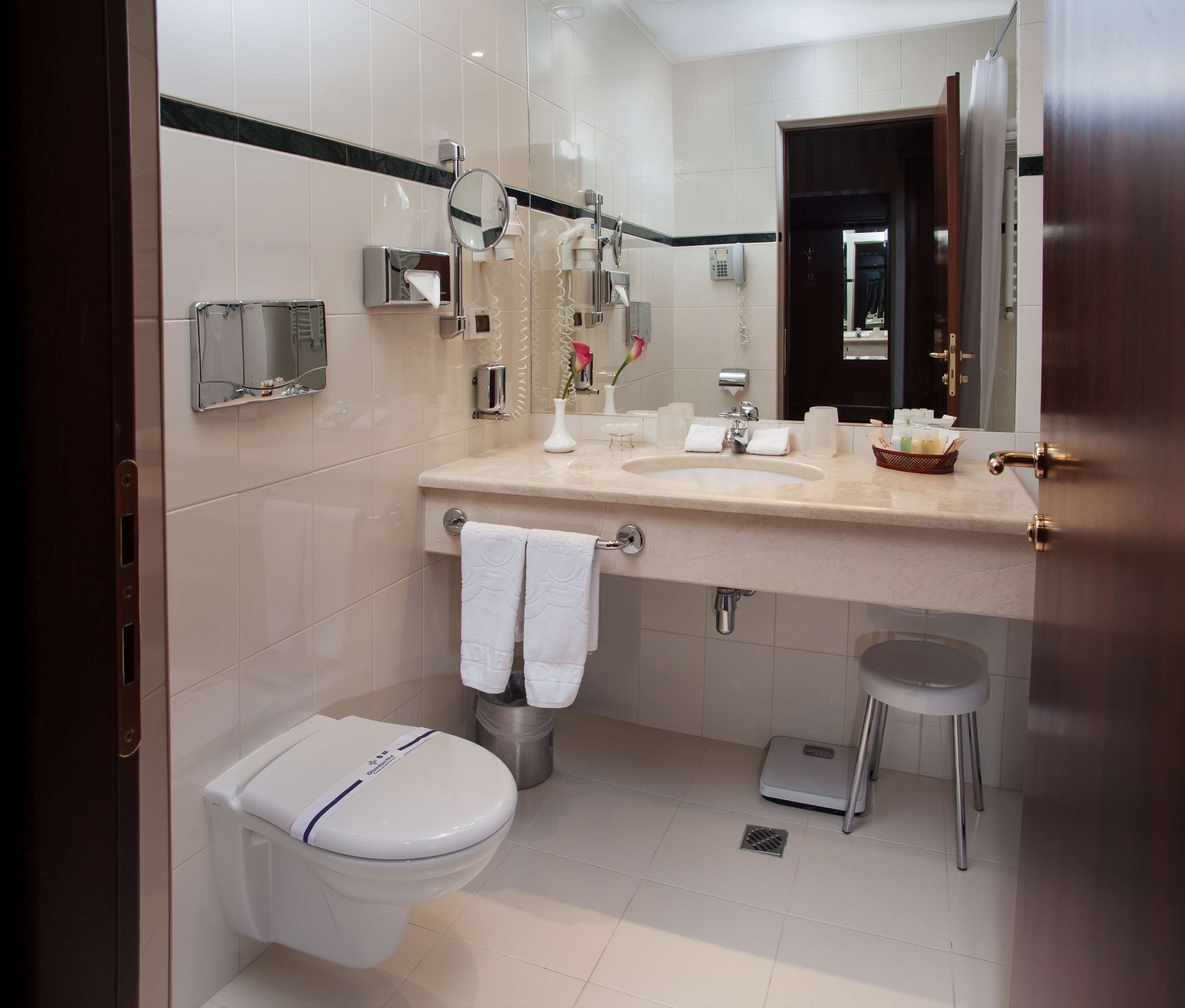 A modern bathroom with a toilet, sink, and mirror.