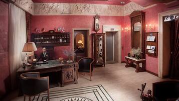 A lobby with a reception desk, chairs, a clock, and a wall with decorative panels.