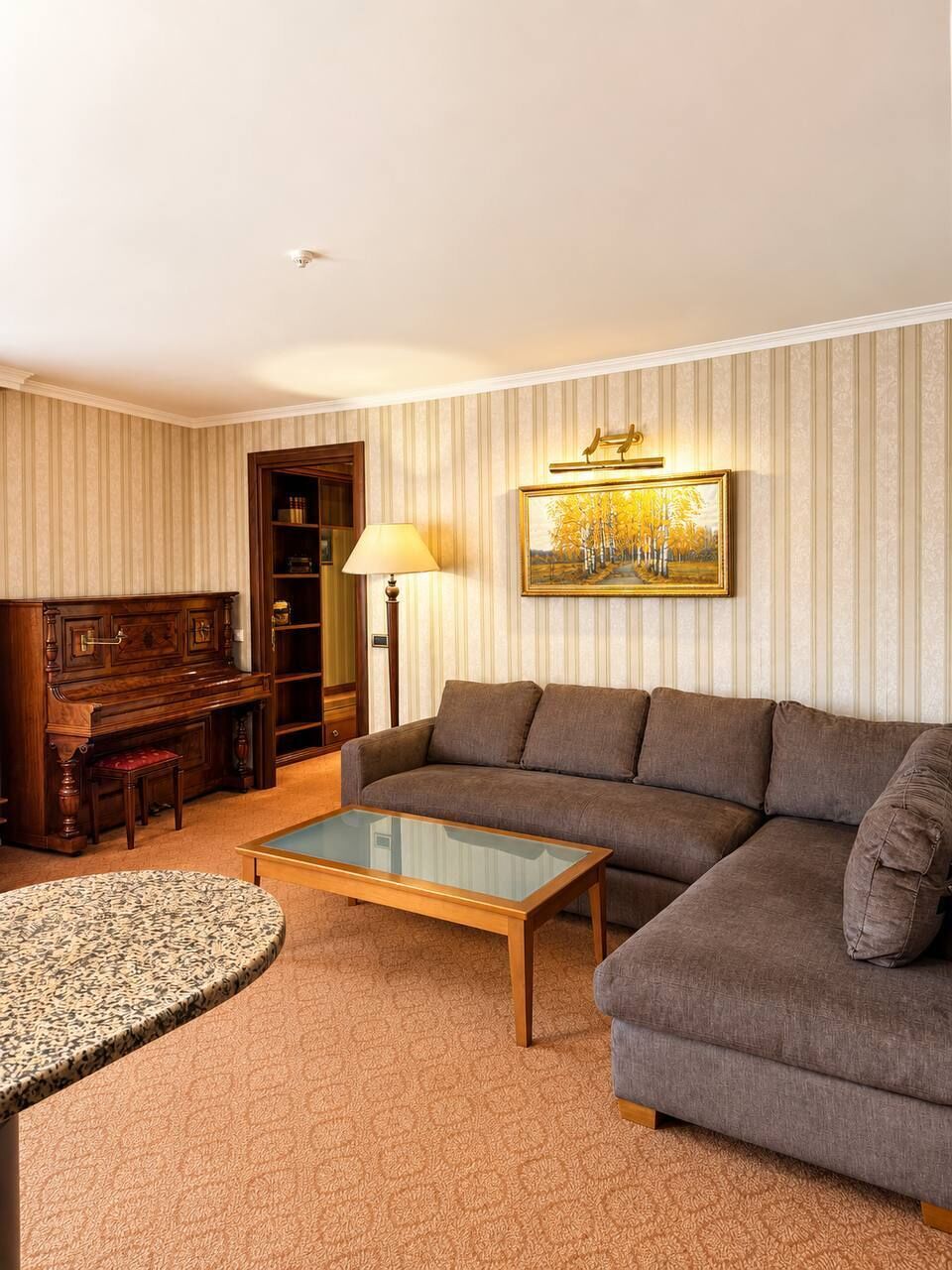 Una sala de estar con un piano, sofá, mesa de centro y una lámpara.