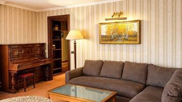 Una sala de estar con un piano, sofá, mesa de centro y una lámpara.