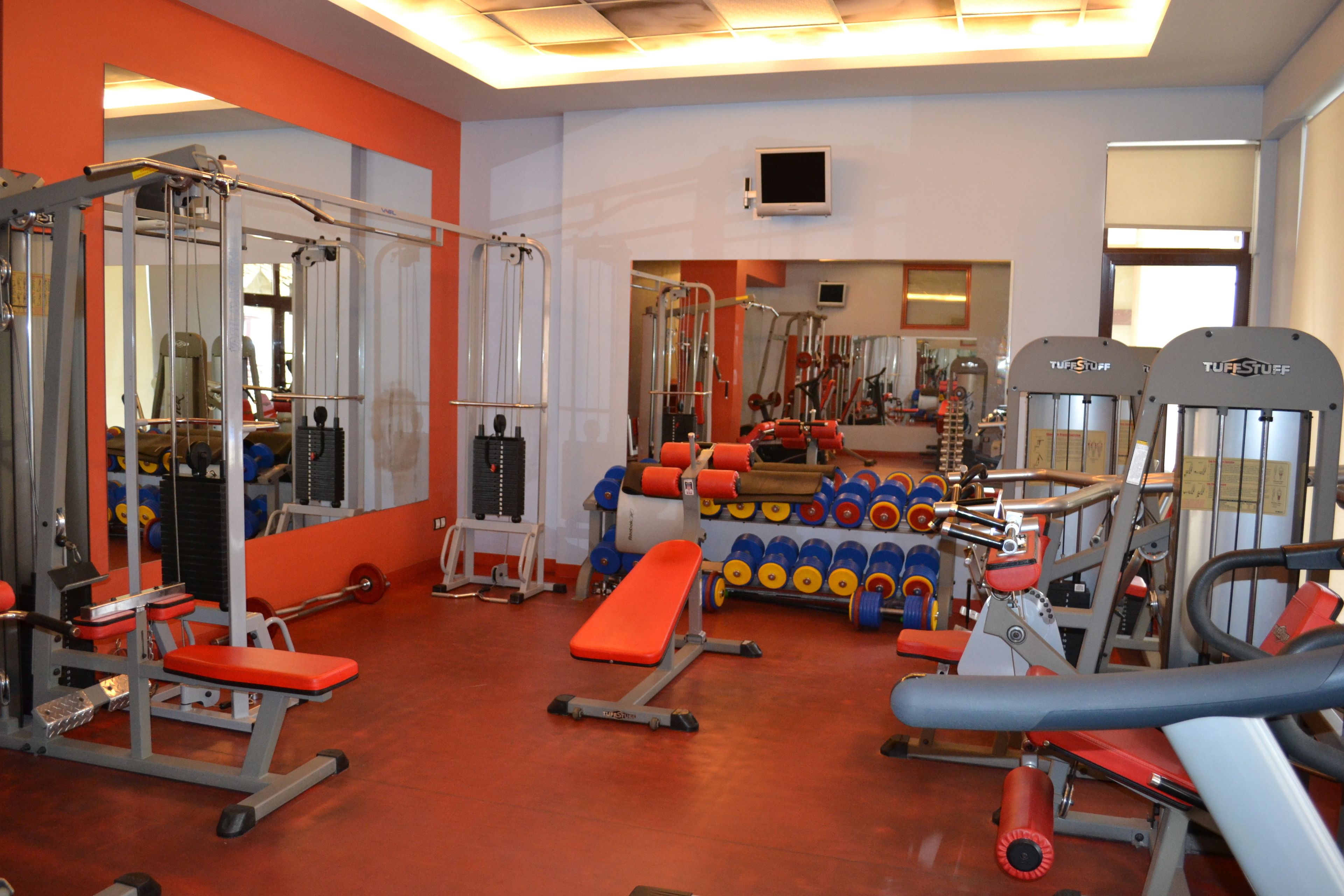 A gym with various exercise equipment, including benches, weight machines, and dumbbells.