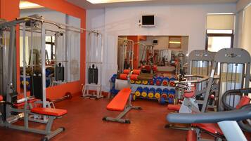 A gym with various exercise equipment, including benches, weight machines, and dumbbells.