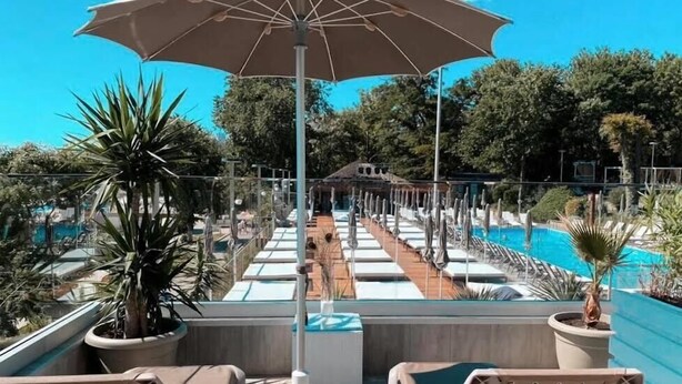 A poolside area with lounge chairs, a table, and an umbrella. - Hotel Otrada (Odesa)