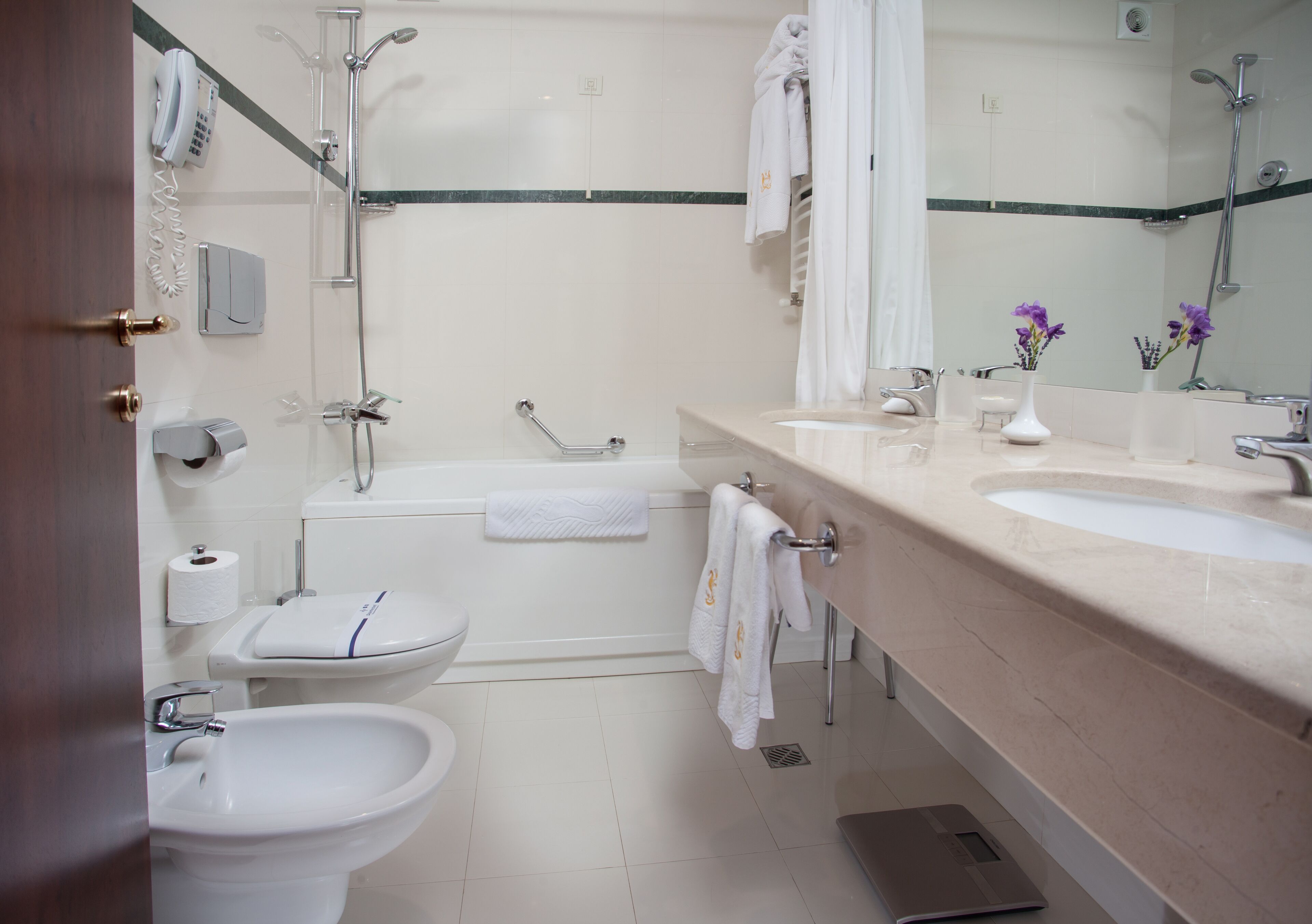 A modern bathroom with a bathtub, two sinks, a toilet, and a bidet.