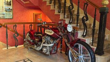 Een rode trap met gedetailleerde zwarte leuningen, een klassieke motorfiets en een groot rond vloerontwerp.