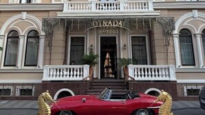 A hotel with a grand entrance, a red convertible parked in front, and a decorative pool area. - Hotel Otrada (Odesa)