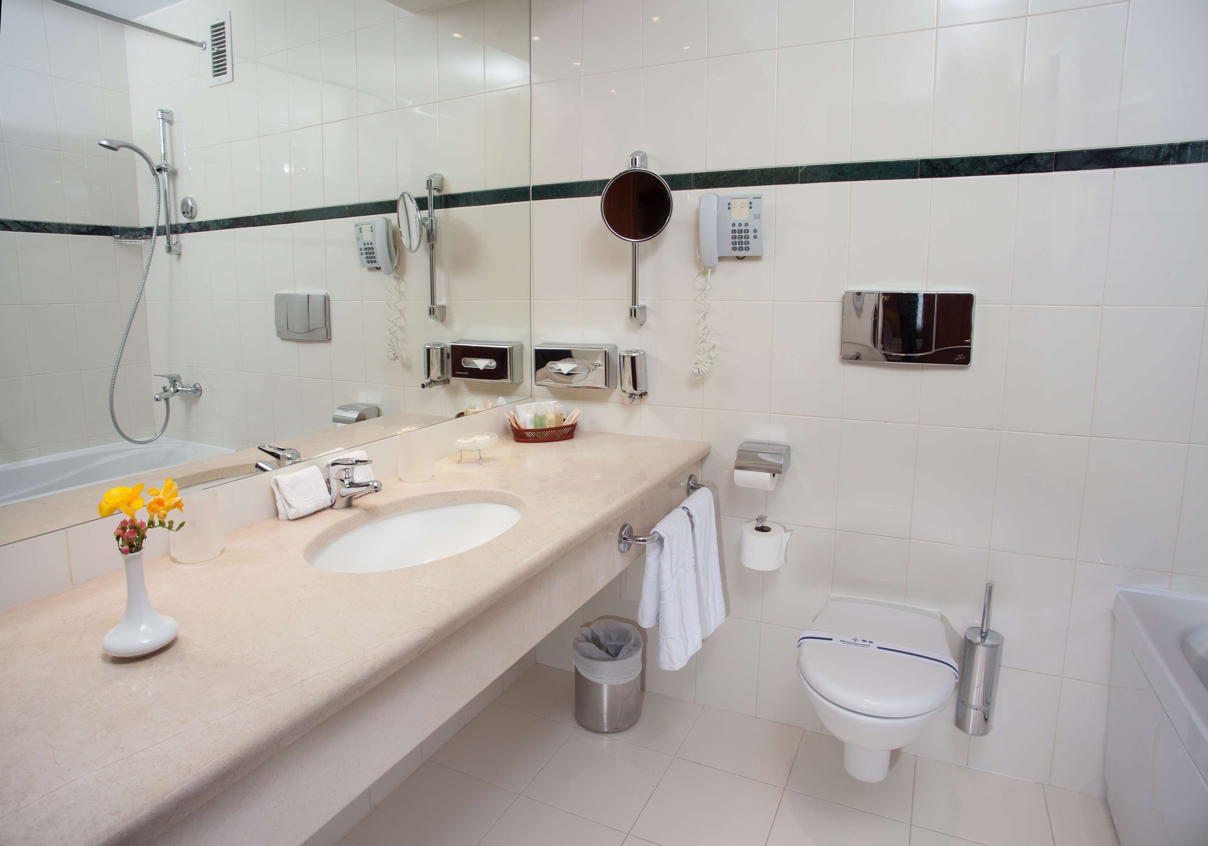 Une salle de bain moderne avec un grand miroir, un lavabo, des toilettes et une douche.