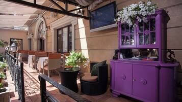 A terrace with outdoor seating, a purple cabinet, and a TV mounted on the wall.