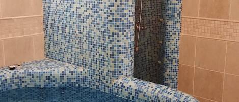 Un jacuzzi con paredes de mosaicos y una zona de ducha.