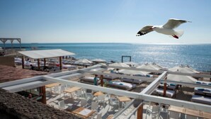 A beachside hotel with outdoor seating, umbrellas, and a view of the sea. - Hotel Otrada (Odesa)