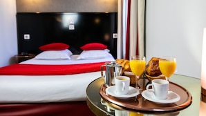 A hotel room with a bed, breakfast tray, and a nightstand. - Eiffel Villa Garibaldi (Paris)