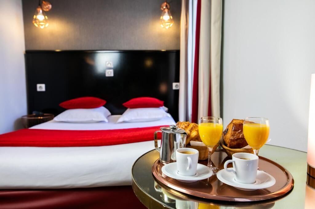 Une chambre d’hôtel avec un lit, un plateau contenant des articles pour le petit-déjeuner et une vue sur l’intérieur de la pièce.