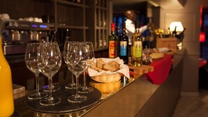 A bar area with wine glasses, bottles, and a basket of bread. - Eiffel Villa Garibaldi (Paris)