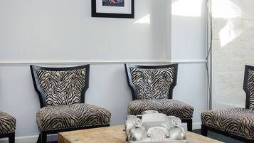 A conference room with a wooden table, zebra-patterned chairs, a framed picture on the wall, and a window with blinds.