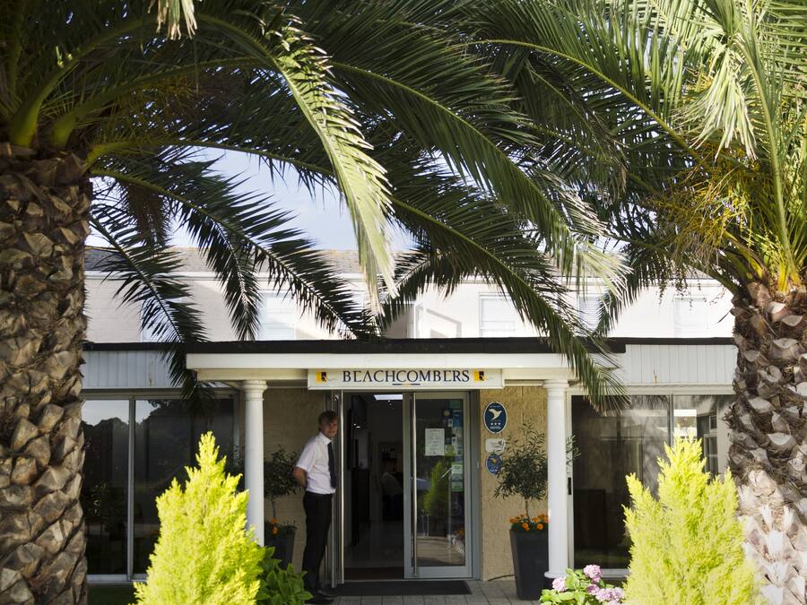 A building with a sign reading "Beachcombers" and a person standing at the entrance.
