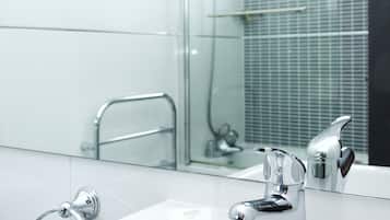 Un baño moderno con lavamanos blanco, grifería cromada y cabina de ducha con mampara de vidrio.