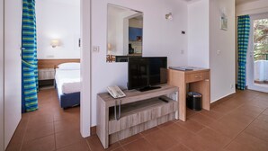 Habitación de hotel con cama, televisión, escritorio y baño visible a través de una puerta abierta.