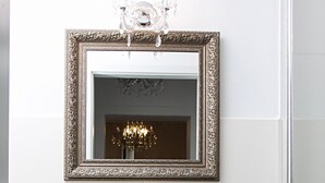 A bathroom with a freestanding sink, a mirror with an ornate frame, and a chandelier. - Hotel Lux (Düsseldorf)