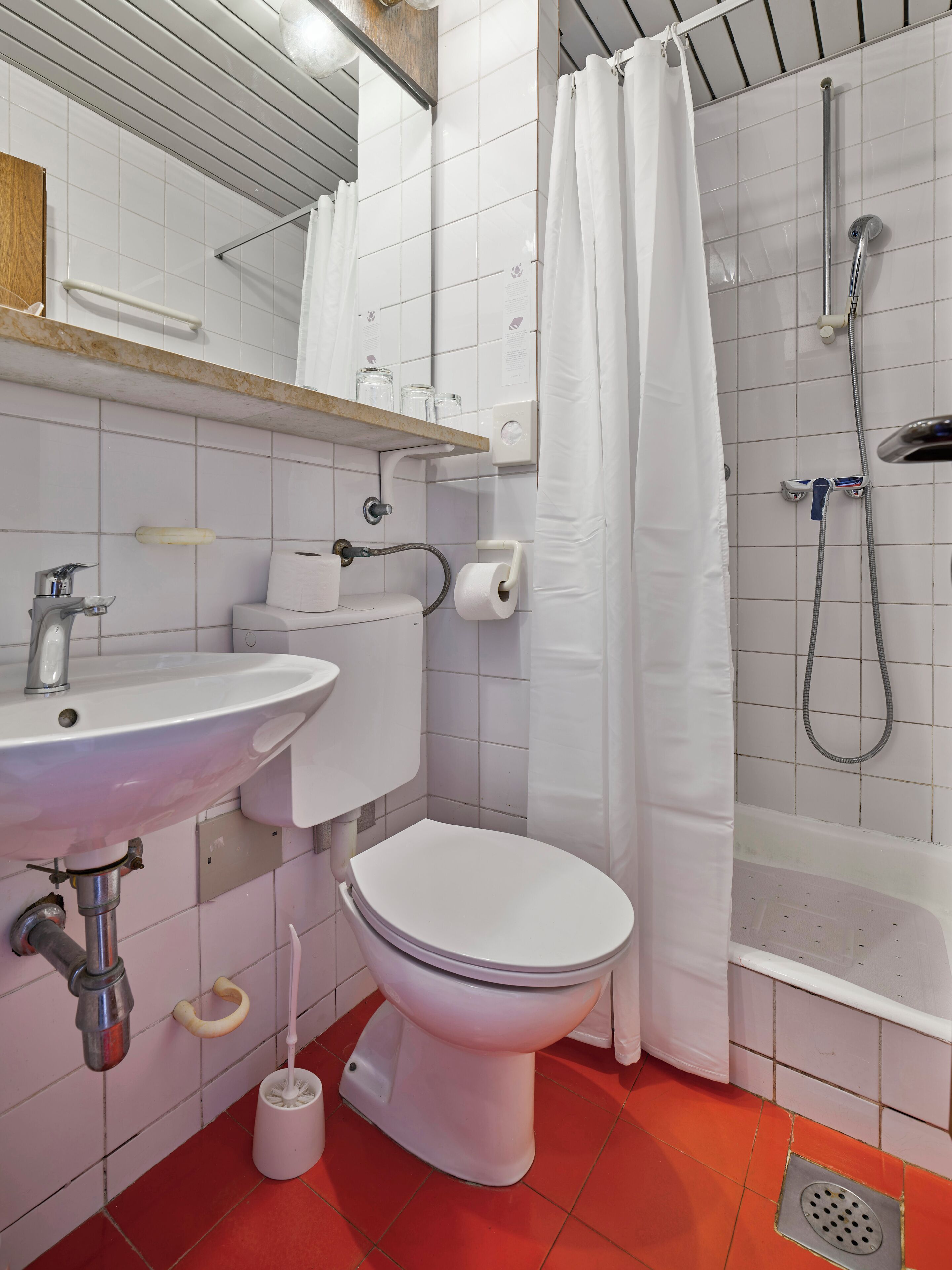 A bathroom with a white sink, toilet, and shower.