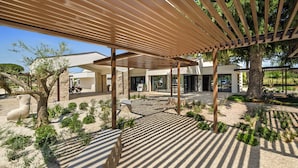 Un espacio exterior moderno con una pérgola, esculturas de piedra y un sendero pavimentado.