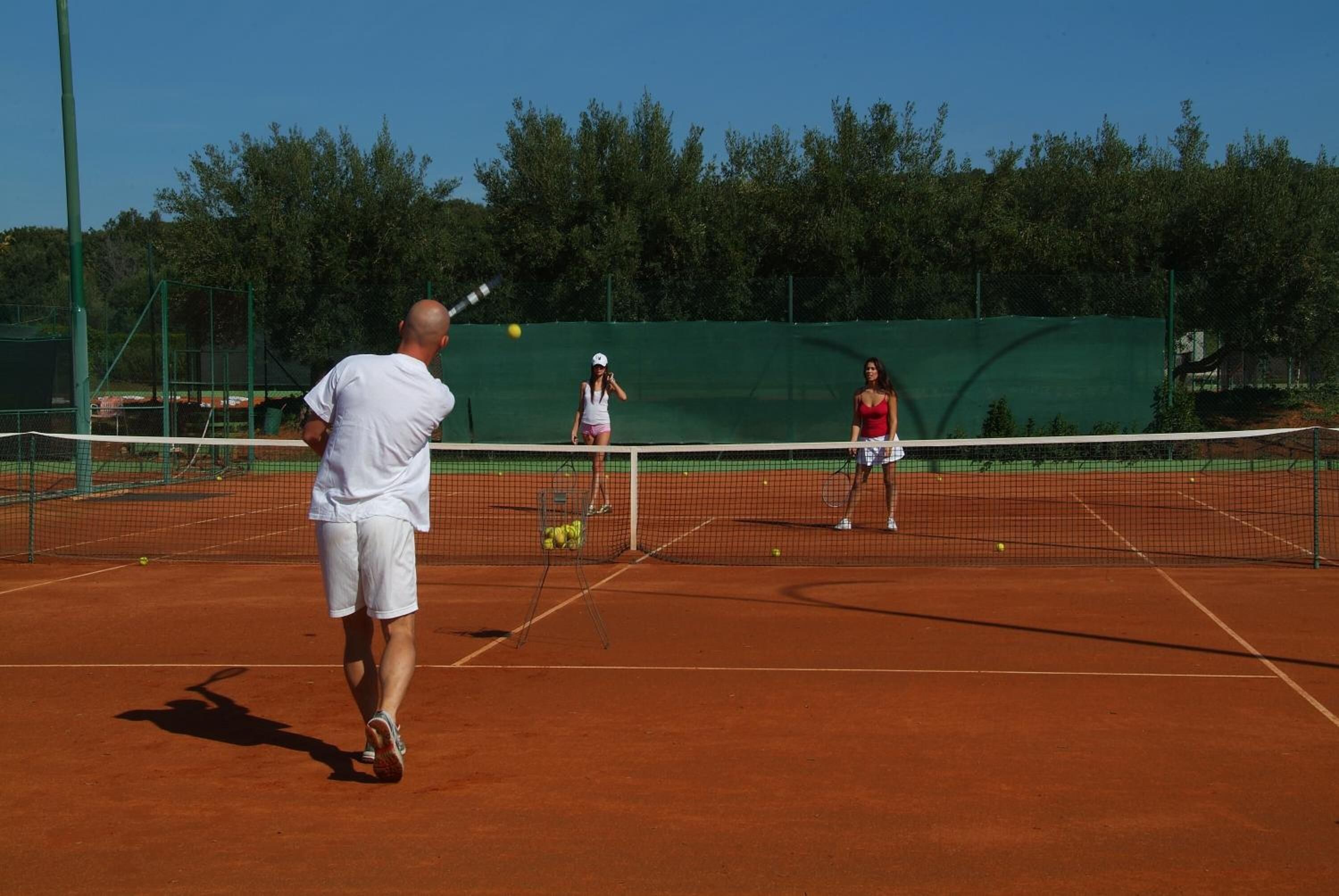 A tennis court with a net, a player in white, and another player in red.