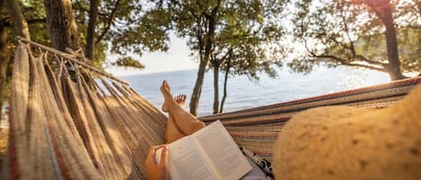 En la playa, camastros, sombrillas y bote de remos o canoa
