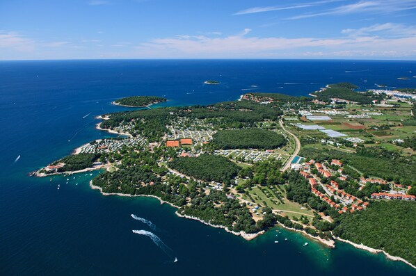 Vue aérienne d’une ville côtière avec un port de plaisance, des zones résidentielles et des espaces verts.
