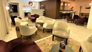 Un espace lounge moderne avec des canapés et des fauteuils, un comptoir d’accueil et un bar.