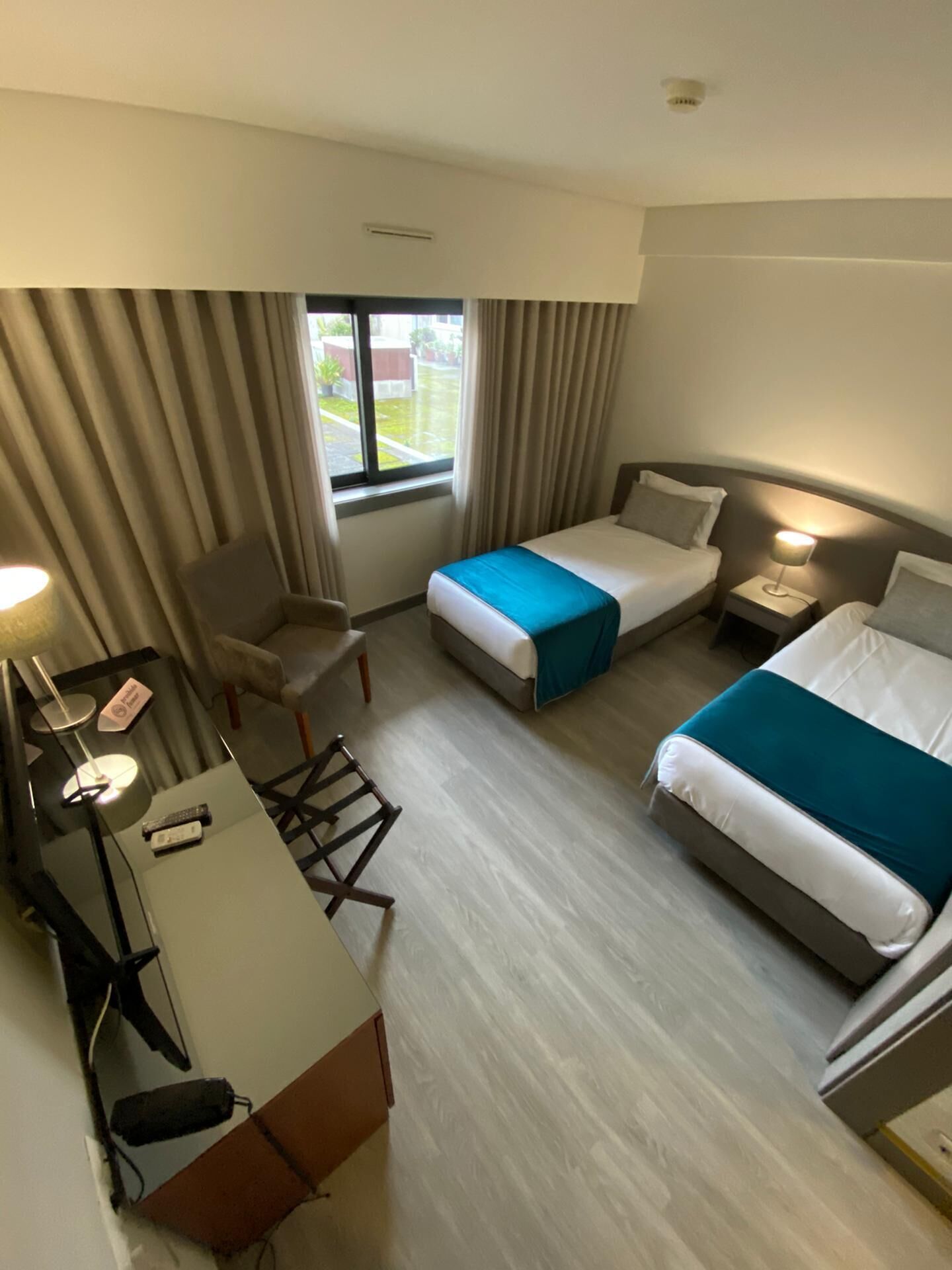 A hotel room with two beds, a desk, a chair, and a window with curtains.