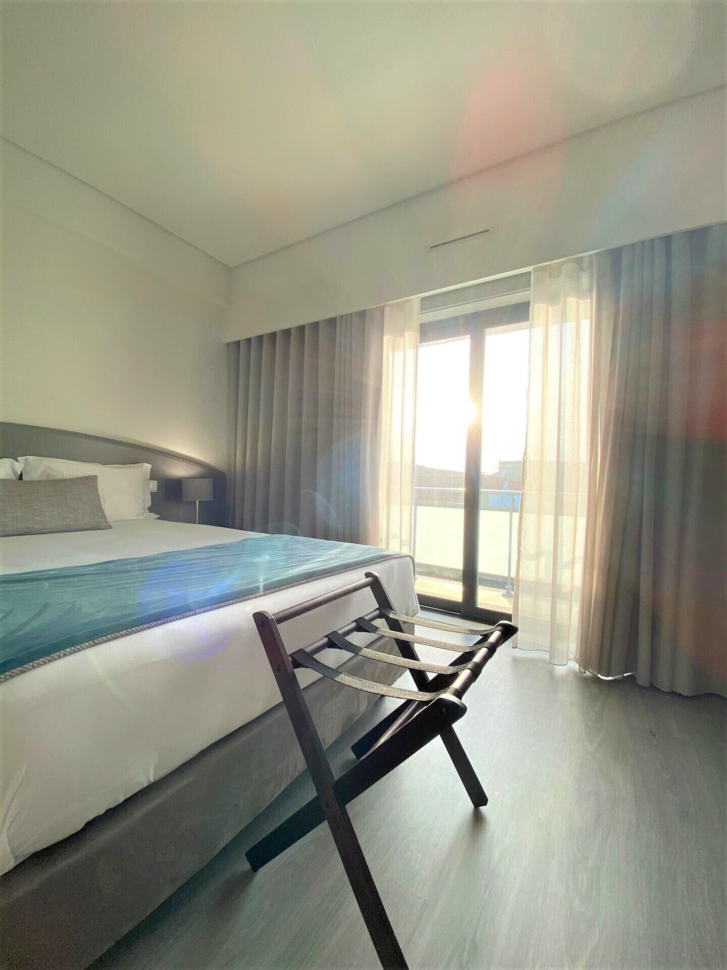 Una habitación de hotel moderna con una cama grande, un escritorio y vistas al exterior.