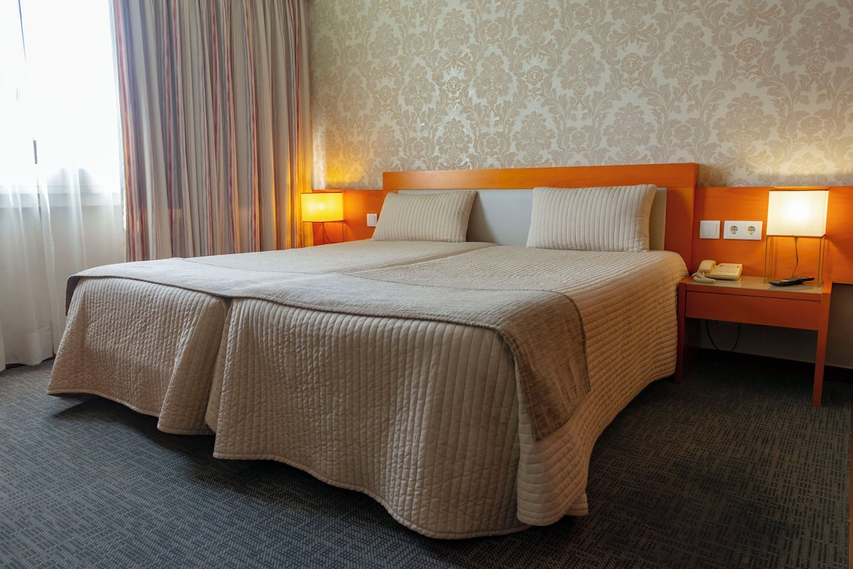 A hotel room with a large bed, two bedside tables, a lamp, and a telephone.