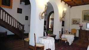 A dining area with a wooden staircase, white walls, and a chandelier. - Hotel Villa Maria (Sanremo)