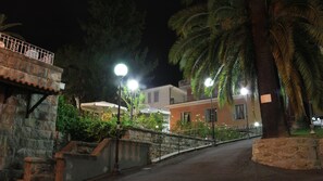 A nighttime street scene with stone walls, a metal railing, and a street lamp. - Hotel Villa Maria (Sanremo)