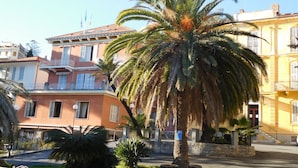 A building with a balcony and a palm tree in front. - Hotel Villa Maria (Sanremo)