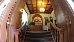 A grand staircase with a wooden railing leading to a bar area with a chandelier. - Hotel Villa Maria (Sanremo)