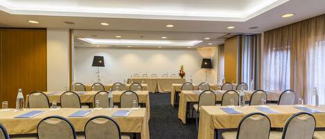 Un salón de conferencias con varias mesas, sillas y un atril.