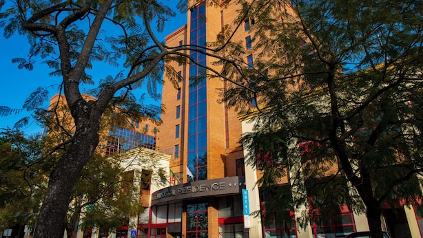 Un hotel con un diseño arquitectónico moderno, que destaca por una fachada de vidrio vertical y una combinación de colores rojo y blanco.