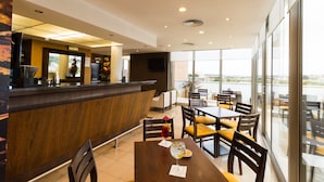 Un moderno vestíbulo de hotel con mostrador de recepción, zona de estar y ventanas amplias que ofrecen vistas al exterior.