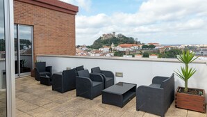 Terraza en la azotea con mobiliario exterior y vistas a un castillo histórico.