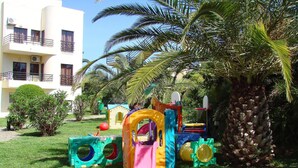 A children's play area with colorful play structures and a palm tree. - Clube Alvorferias (Portimão)