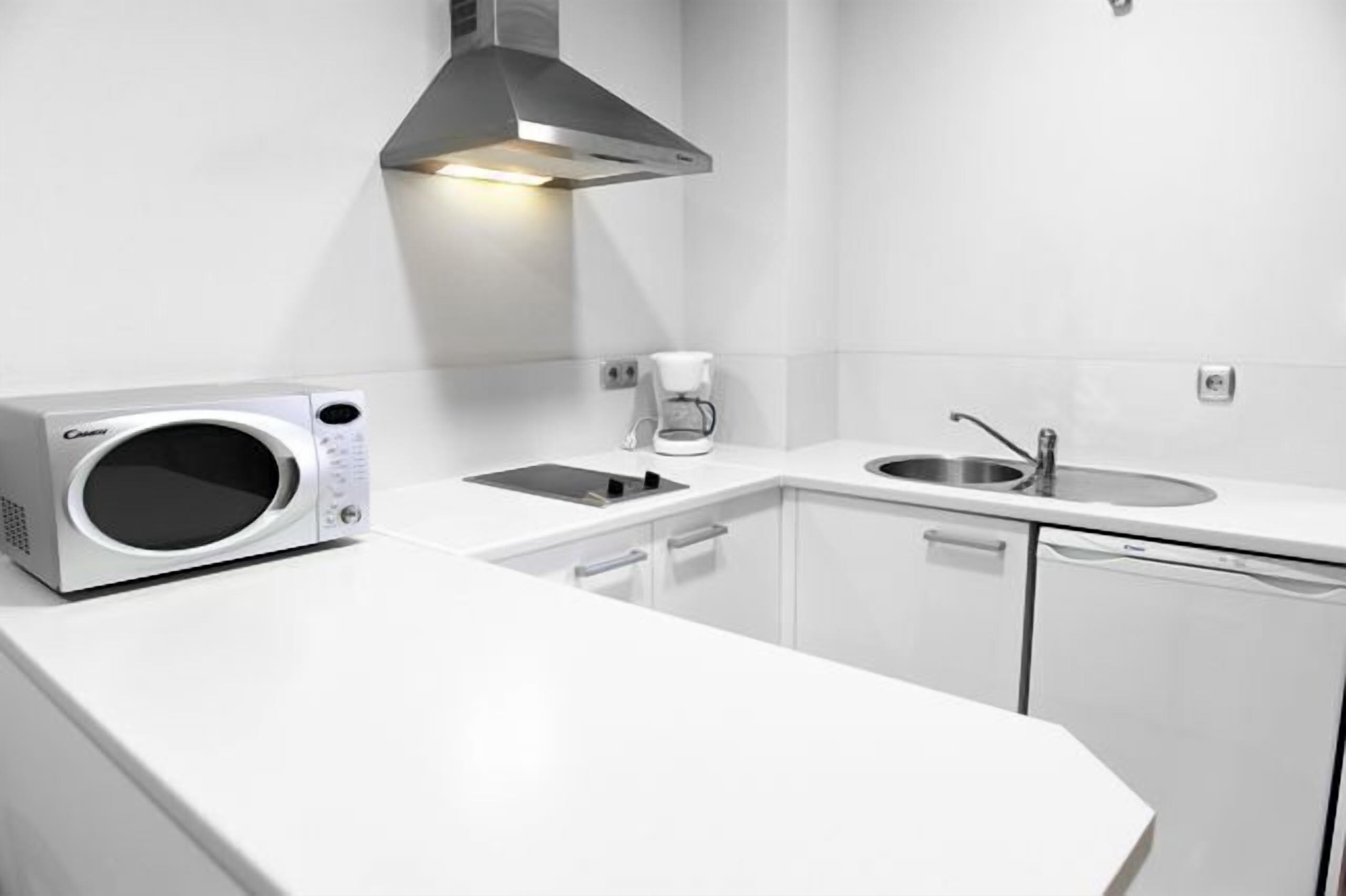 Una cocina moderna con microondas integrado, cafetera y lavabo.