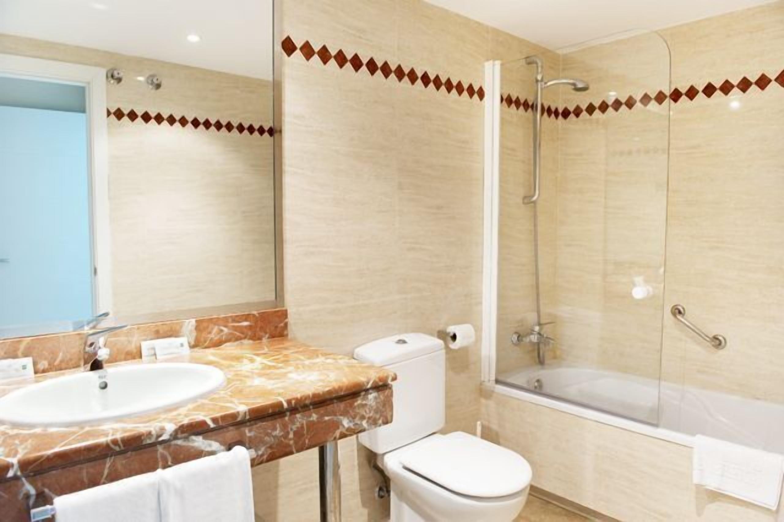 Un baño moderno con tocador de mármol, inodoro, ducha y bañera.