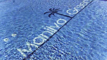 Una piscina con una palmera y el texto "Marina del Oro" sobre la superficie del agua.