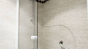Un baño moderno con ducha envuelta en vidrio, una bañera blanca y un revestimiento de pared con diseño de rombos.