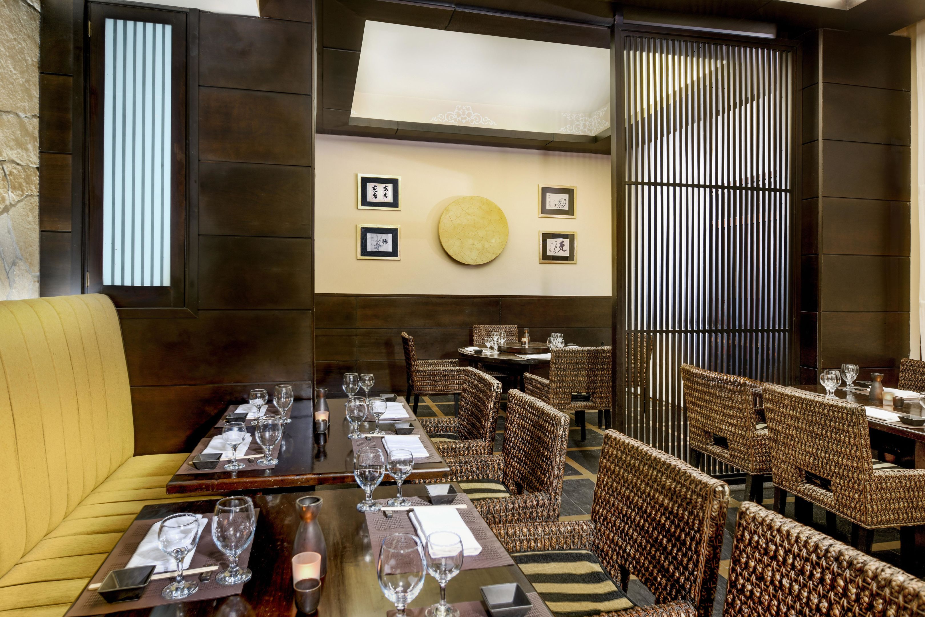 A restaurant with wooden furniture, framed pictures on the wall, and a round table in the center.