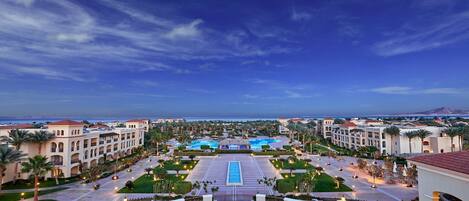Un resort con piscina central, varias construcciones y vista al océano.