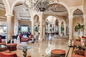 A spacious lobby with high ceilings, a grand chandelier, and a central fountain.