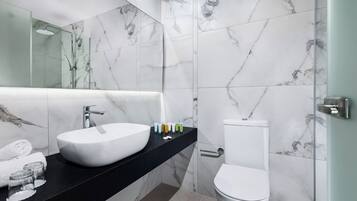 Um banheiro moderno com uma pia grande e branca, bancada preta, vaso sanitário e paredes com padrão marmorizado.