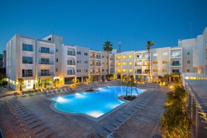 Un hôtel doté d’une piscine, entourée de transats et de palmiers.